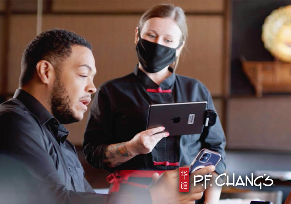 PF Changs Server using tableside mobile POS with PF Changs Logo