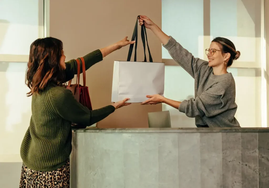 Store associate handing retail bag to customer