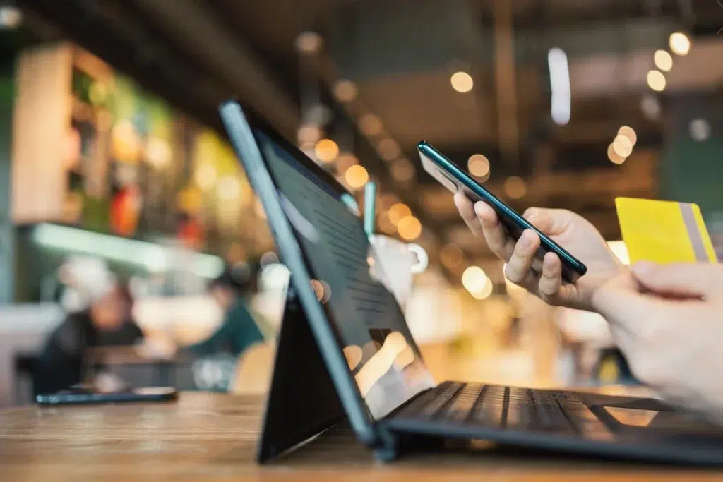 Owner looking at iPad at restaurant table while holding phone and credit card