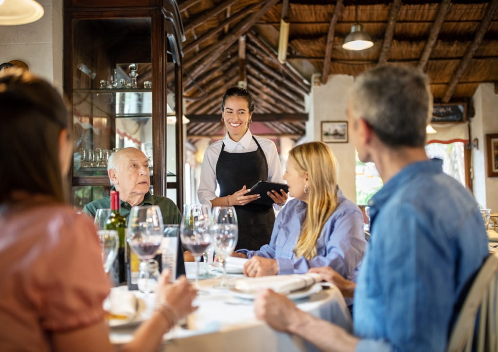 Waitress in small restaurant type taking tableside ordering with tablet.