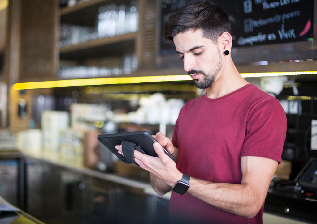 Waiter holding handheld pos in restaurant.